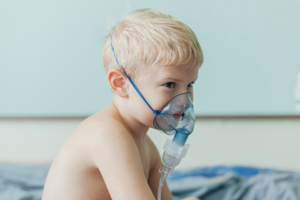 Infant baby with oxygen face mask and respiratory infection in hospital.